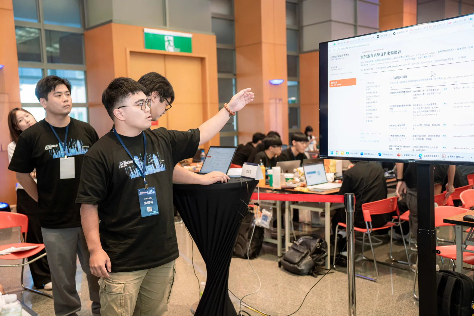 A team member of AI城市起風 explaining the system screen to judges and other teams in the competition hall